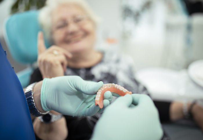 Dentist showing teeth dentures to a patient